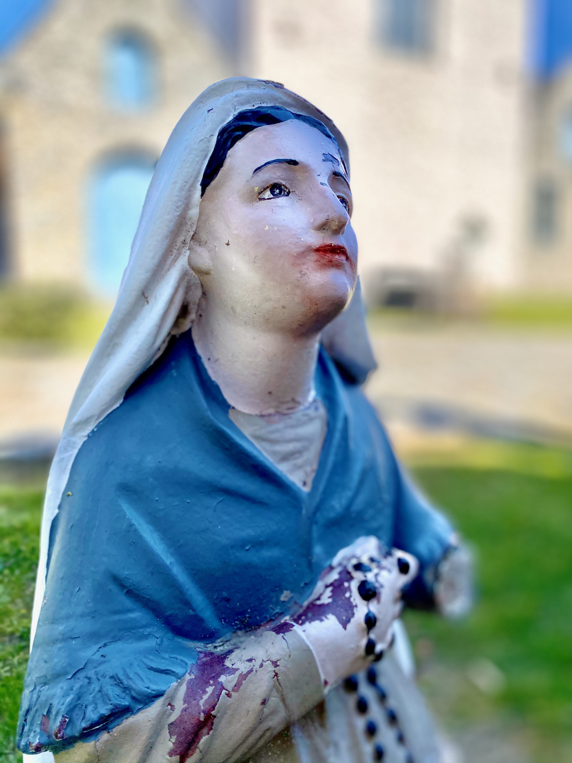 Beeld van knielende Bernadette aan Mariagrot bij de Sint-Laurentiuskerk te Ename